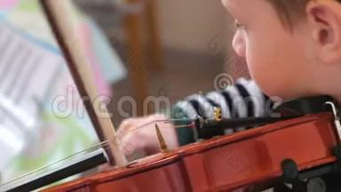 八岁的男孩正在<strong>学习</strong>拉小提琴。 用<strong>音符</strong>播放音乐。